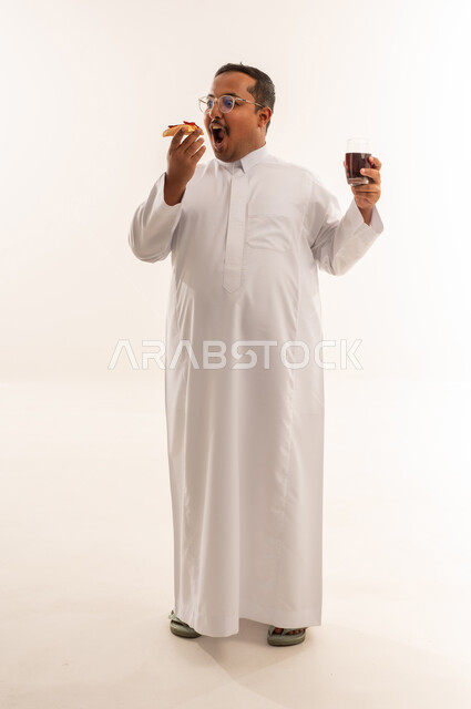 رجل سعودي بالثوب يتناول البيتزا والمشروب الغازي