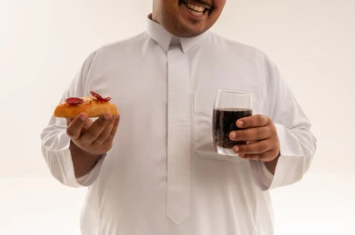 رجل سعودي يعاني من السمنة مع بيتزا ومشروب غازي