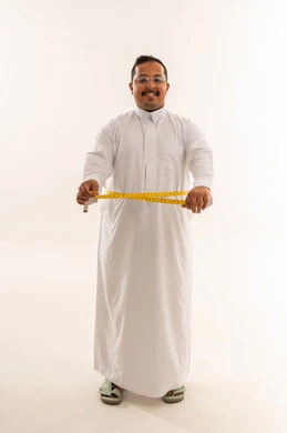 رجل سعودي يقيس خصره بالثوب الأبيض في استوديو