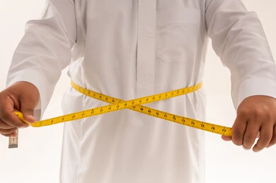 رجل سعودي يقيس محيط الخصر بالثوب الأبيض
