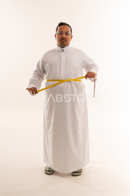 رجل سعودي يعاني من السمنة يقيس خصره بالثوب