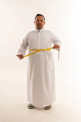 رجل سعودي يعاني من السمنة يقيس خصره بالثوب
