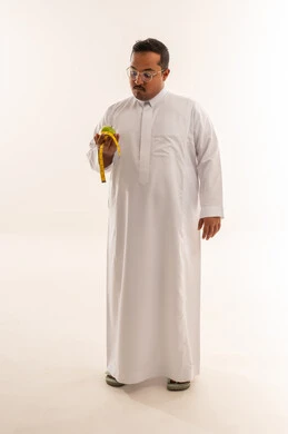 رجل سعودي مع تفاحة وشريط قياس لمفهوم الدايت