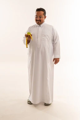 رجل سعودي مع تفاحة وشريط قياس على خلفية بيضاء