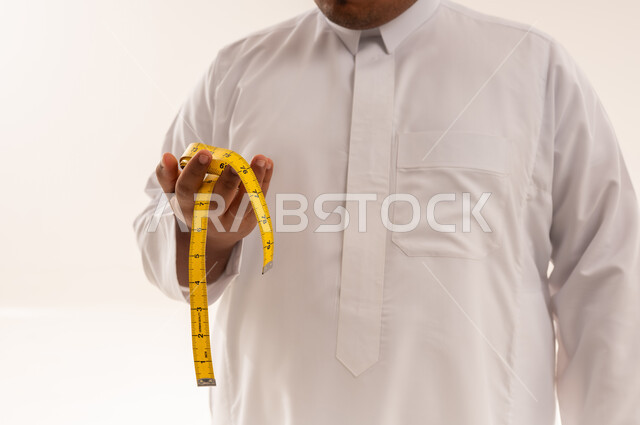 رجل سعودي يعاني من السمنة يمسك بشريط قياس أصفر