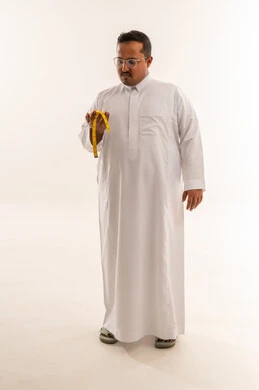 رجل سعودي يحمل شريط قياس الوزن بخلفية بيضاء