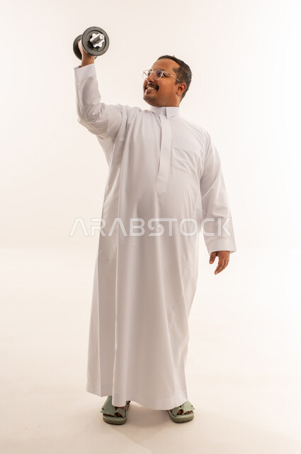 رجل سعودي بالثوب يرفع الأثقال بخلفية بيضاء