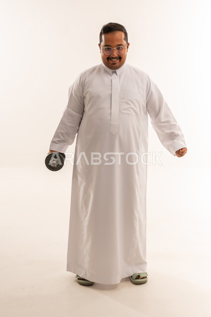 رجل سعودي بوزن زائد يحمل دمبل في استوديو