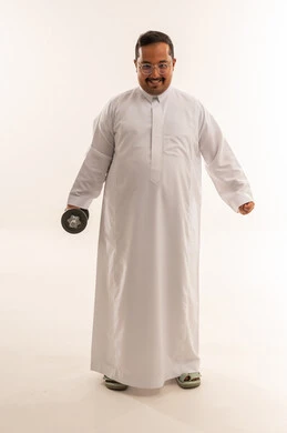 رجل سعودي بوزن زائد يحمل دمبل في استوديو