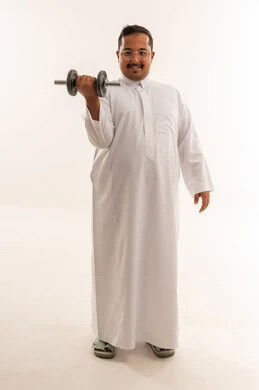 رجل سعودي يرتدي الثوب يرفع الدبل في استوديو أبيض