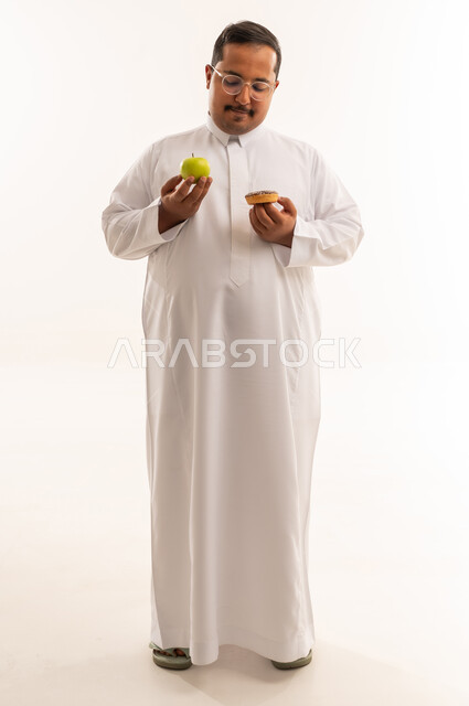 رجل سعودي يختار بين التفاح والدونات خلفية بيضاء