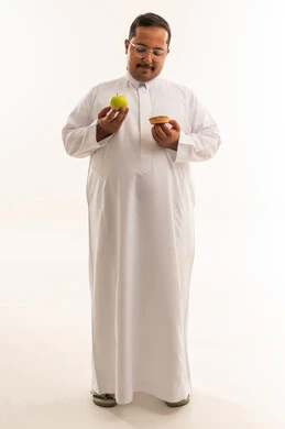 رجل سعودي يختار بين التفاح والدونات خلفية بيضاء