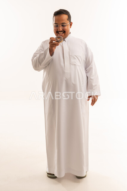 رجل سعودي سمين يأكل الدونات أمام خلفية بيضاء