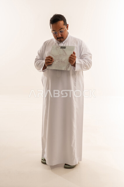 رجل سعودي يعاني من السمنة يحمل ميزان رقمي