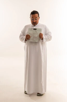 رجل سعودي يعاني من السمنة يمسك ميزان وزن في الاستوديو
