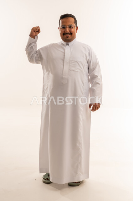 رجل سعودي بالثوب الأبيض يرفع قبضة يده للنجاح