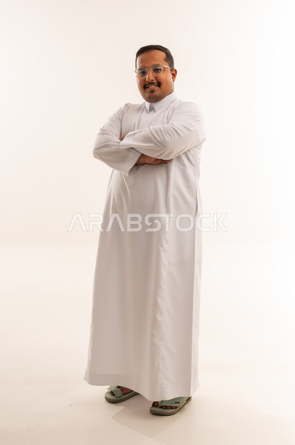 رجل سعودي بالثوب الأبيض يقف أمام خلفية بيضاء