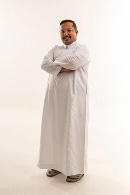 رجل سعودي بالثوب الأبيض يقف أمام خلفية بيضاء