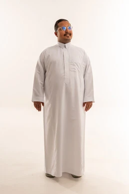 رجل سعودي مبتسم يرتدي الثوب الأبيض في الاستوديو