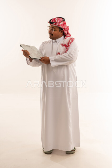 رجل سعودي بدين يمسك ميزان على خلفية بيضاء