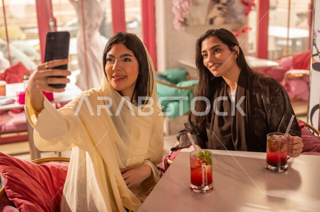 Saudi Women in Abayas Taking Selfie at Cafe