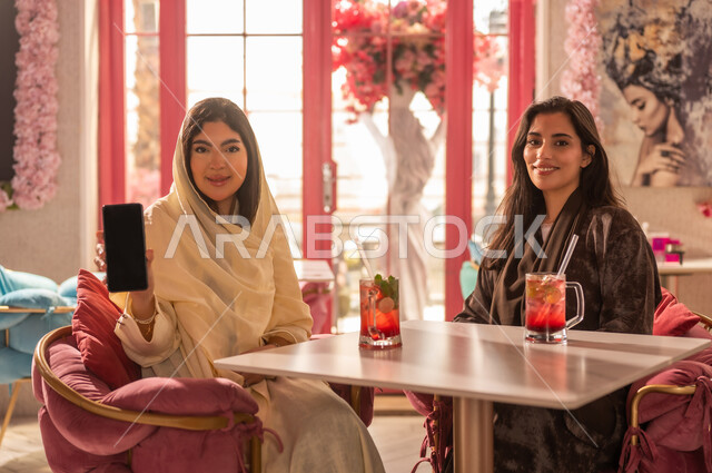 Saudi Women at Cafe Holding Smartphone Blank Screen