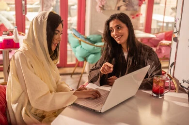 Saudi Women with Laptop in Modern Cafe Setting