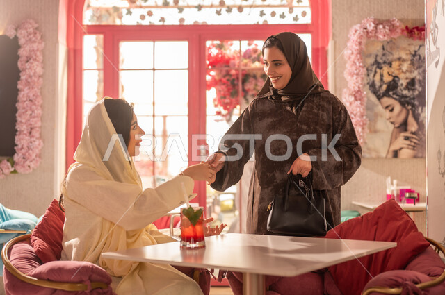 Saudi Women in Traditional Abayas Greeting in Cafe