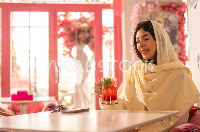 Saudi Woman in Abaya Holding Cold Drink in Cafe