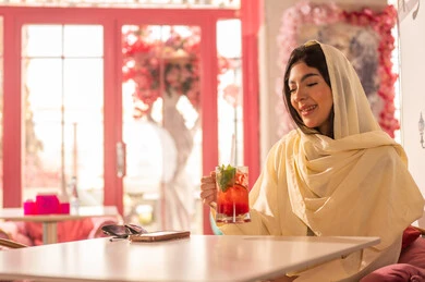 Saudi Woman in Abaya Holding Cold Drink in Cafe