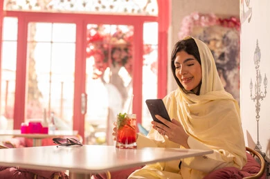 Arab Woman in Beige Shayla Using Smartphone in Cafe