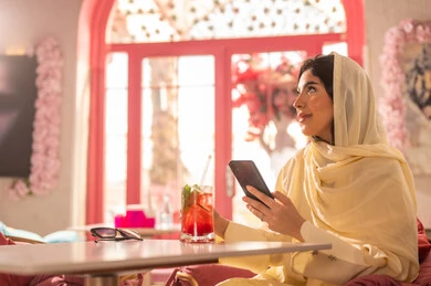 Saudi Woman with Smartphone in Pink Cafe