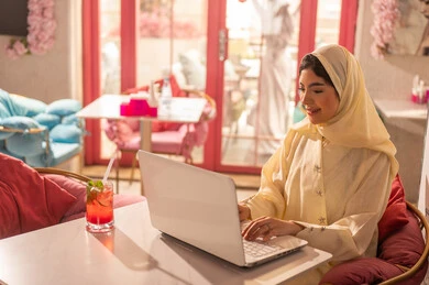 Saudi Woman Working on Laptop in Modern Cafe