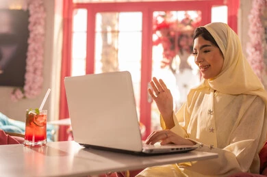 Arab Woman Using Laptop for Video Call in Cafe