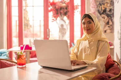 Emirati Woman Working on Laptop in Cafe