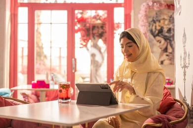 امرأة سعودية تستخدم جهازاً لوحياً في مقهى وردي
