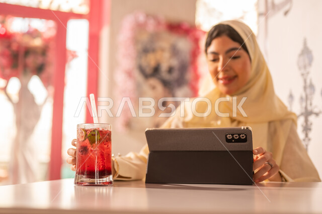 Saudi Woman Using Tablet in Modern Cafe Setting