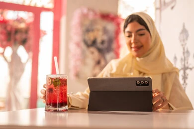 Saudi Woman Using Tablet in Modern Cafe Setting