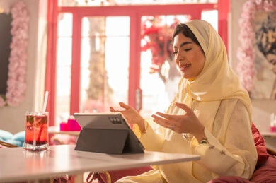 Saudi Woman Using Tablet in Modern Pink Cafe