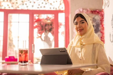 Saudi Woman with Tablet in Pink Modern Cafe