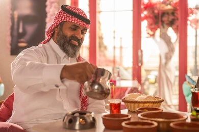 Saudi Man in Traditional Dress Pouring Tea in Cafe