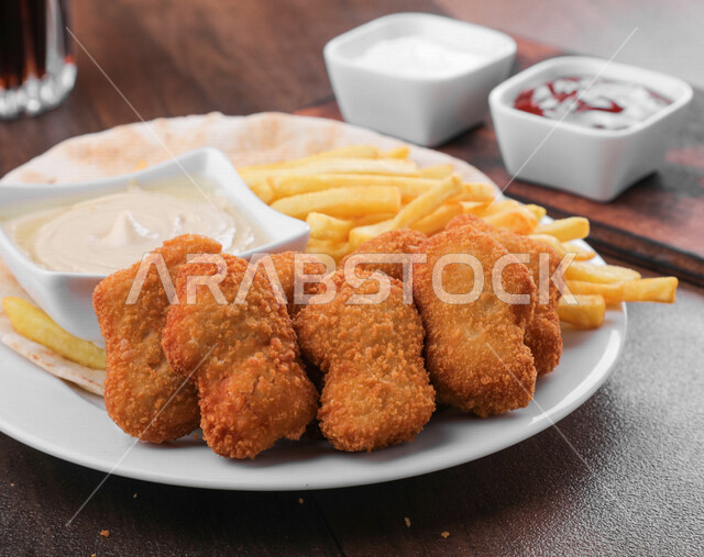Close-up of delicious chicken nuggets with fried potatoes, Arabic meals, delicious recipes and dishes, delicious meals, Saudi Arabian Gulf restaurants