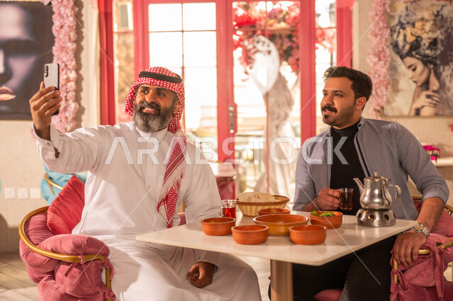 Saudi Men Taking Selfie at Restaurant with Traditional Food