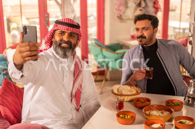 رجال سعوديون يلتقطون سيلفي أثناء تناول الفطور الشعبي