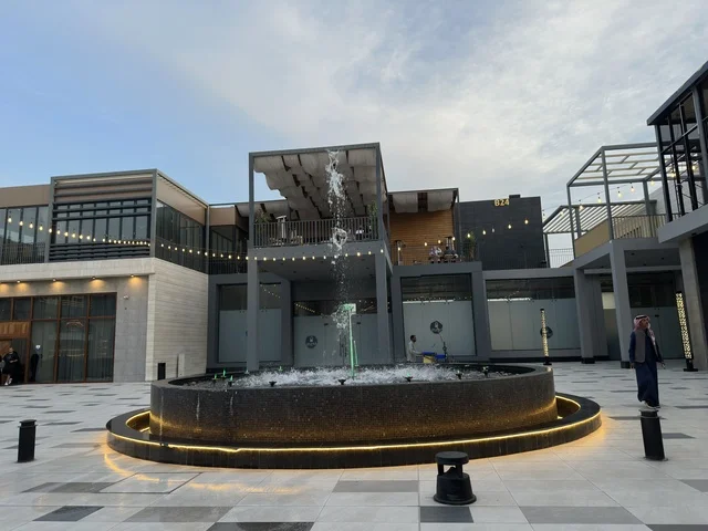 A water fountain and a modern commercial plaza in the Shurfat Park complex in Al Khobar, Saudi Arabia.