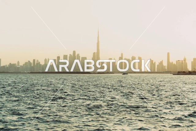 أفق مدينة دبي مع برج خليفة وقت الغروب فوق مياه البحر
