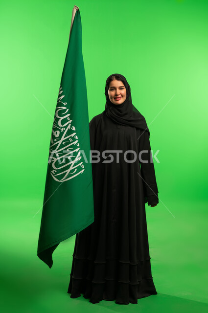 امرأة سعودية مع العلم الوطني بخلفية خضراء