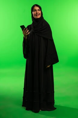 Saudi Woman in Abaya with Smartphone on Green Screen