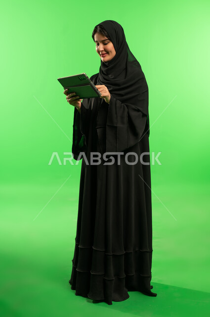 امرأة سعودية تستخدم جهاز لوحي على خلفية خضراء