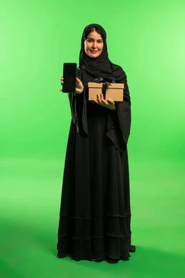 امرأة سعودية بالعباءة مع هدية وهاتف بخلفية خضراء